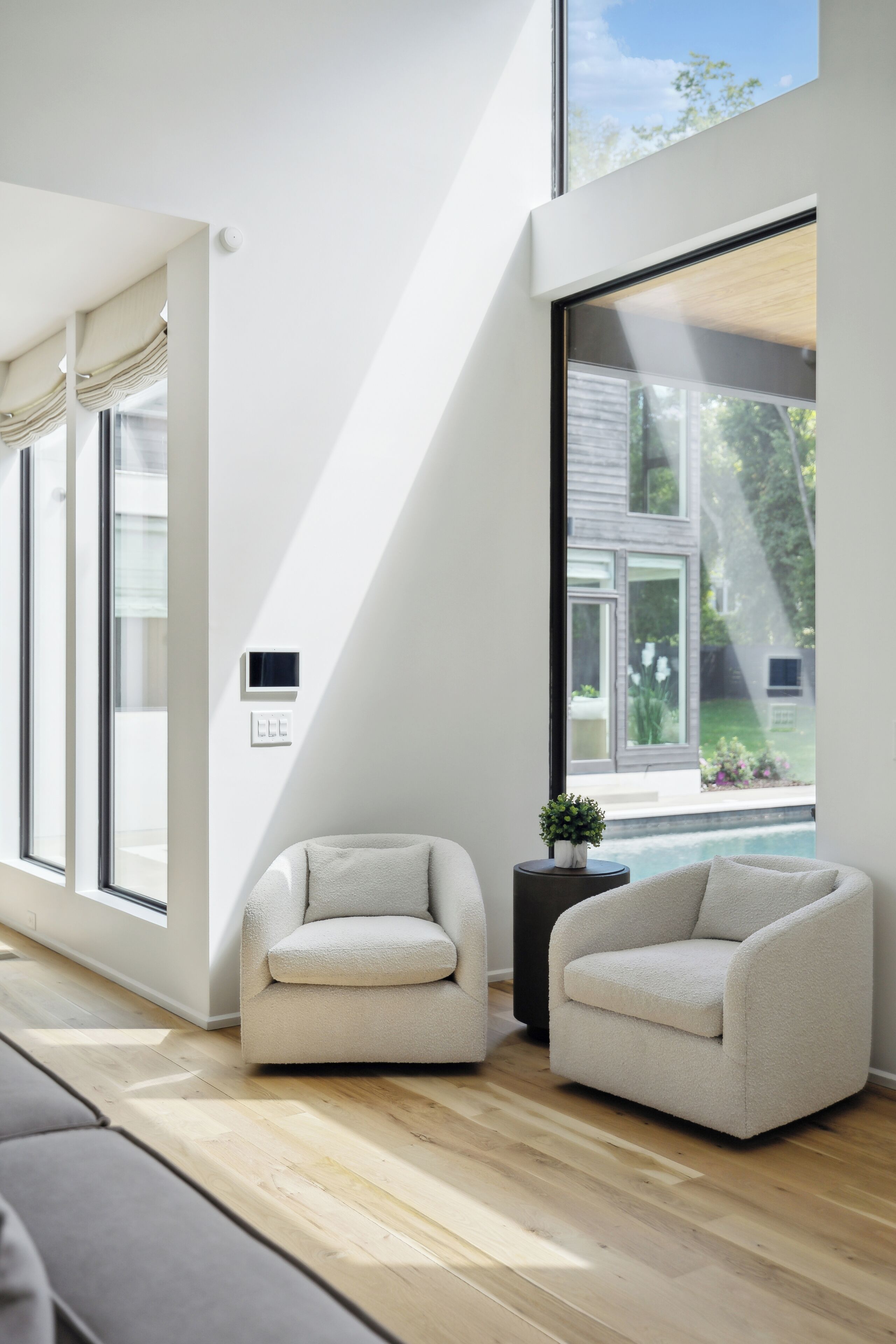 Un salon moderne doté d’une grande fenêtre, de deux fauteuils, d’une petite table d’appoint et d’un radiateur encastré.