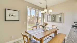A dining area with a wooden table, chairs, and a bench. There is a chandelier above the table and a framed quote on the wall. - Family-friendly Flagstaff Home Near Hiking Trails! (Flagstaff)