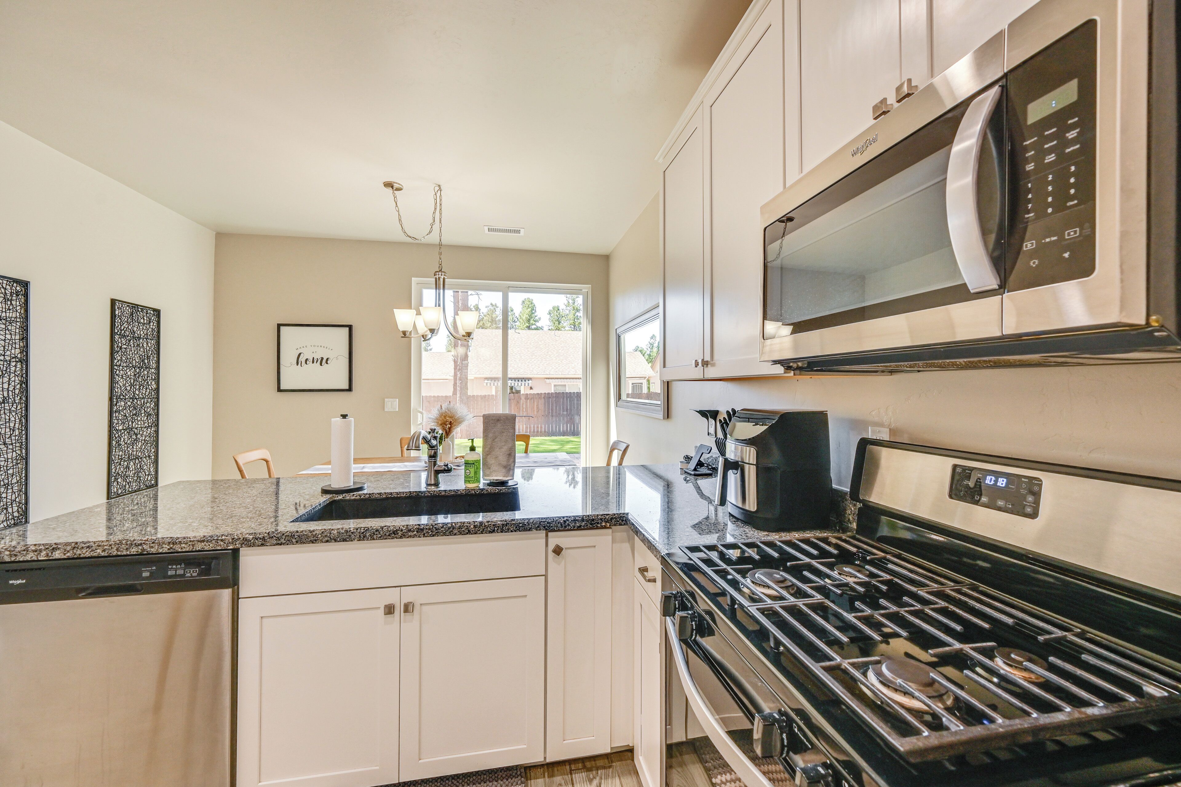 A modern kitchen with a built-in dishwasher, stainless steel appliances, and a large window providing natural light.