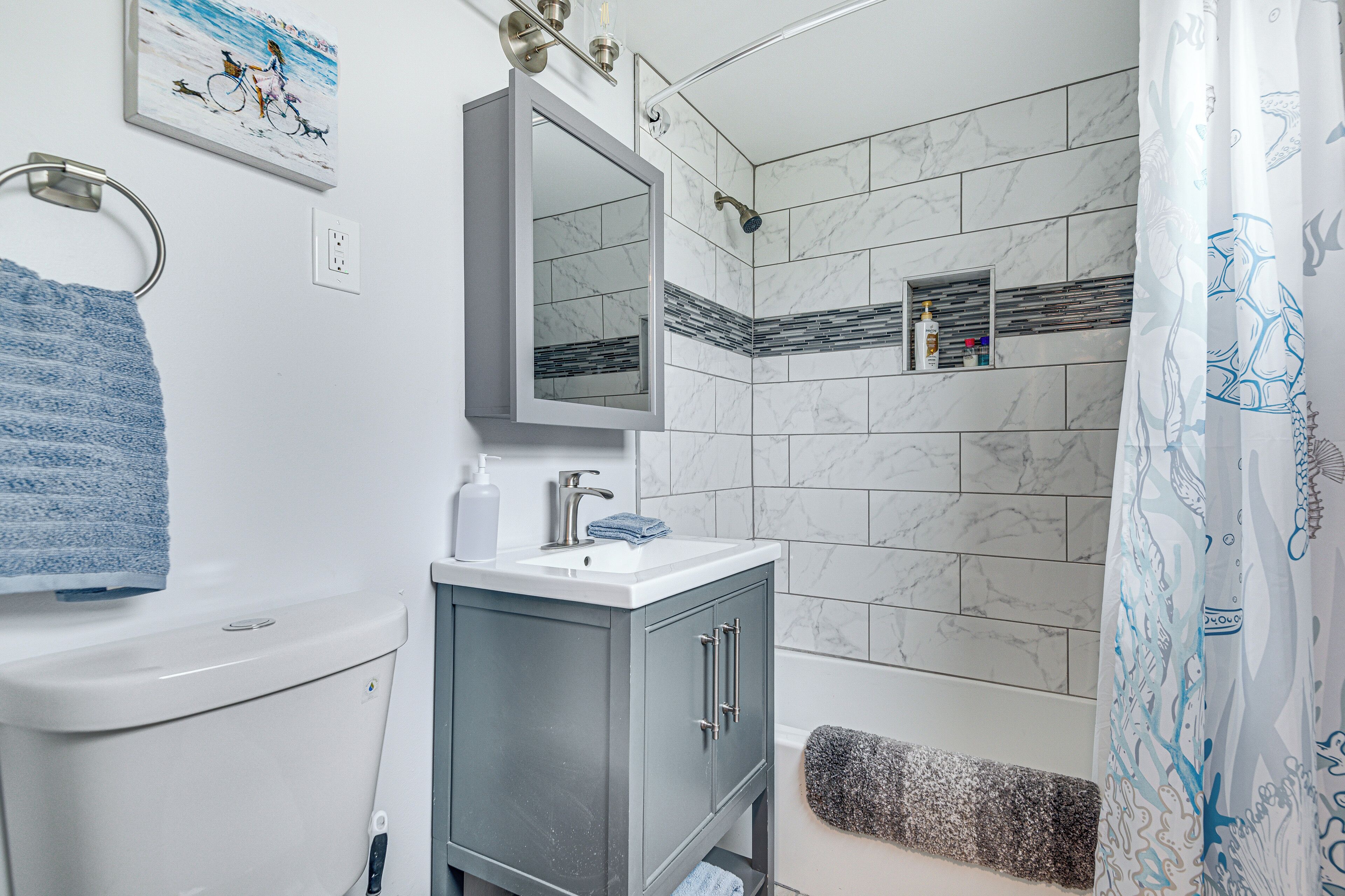 A bathroom with a toilet, sink, mirror, shower, and towel rack.