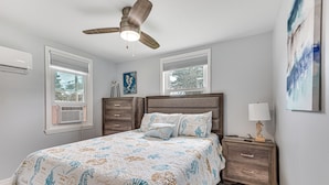 A bedroom with a bed, nightstands, a ceiling fan, and artwork on the walls. - Centrally Located Merritt Island Cottage w/ Deck! (Merritt Island)