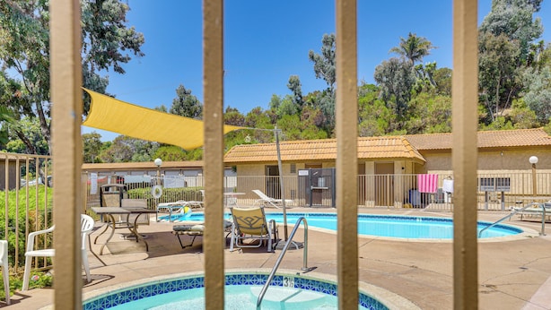 A pool area with a tiled pool, lounge chairs, and a covered seating area. - Oceanside Condo w/ Pool & Hot Tub Access! (Oceanside)
