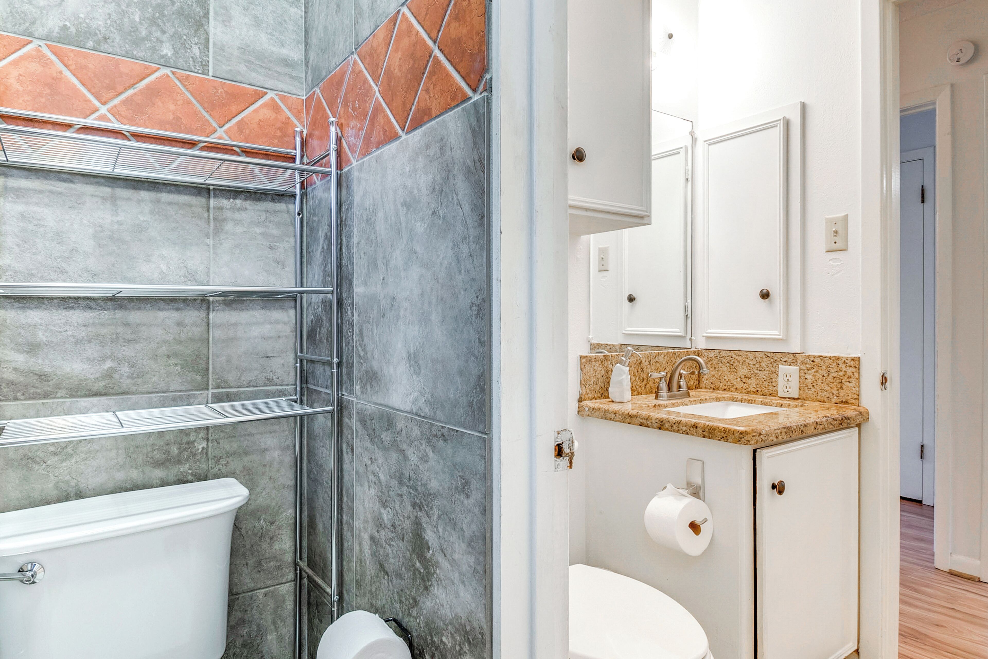 A bathroom with a shower, toilet, sink, and cabinet.