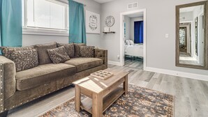 Ein Wohnzimmer mit einem braunen Sofa, einem Holztisch und einem gemusterten Teppich.