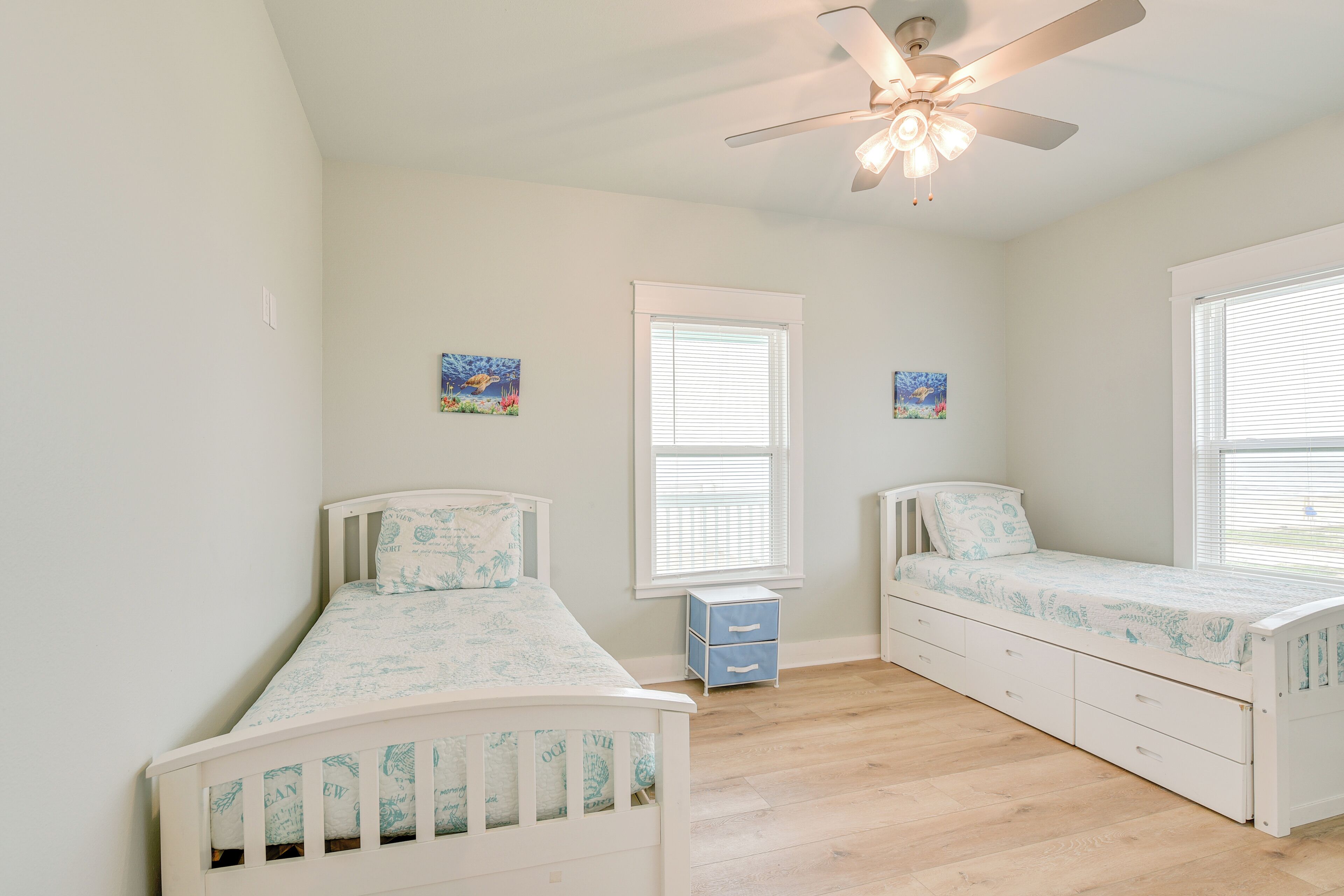 A bedroom with two single beds, a ceiling fan, and a window with blinds.