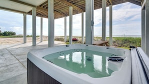 A hot tub under a wooden pergola with a view of the beach. - Hot Tub, Beach Access! Bay-view Gilchrist Retreat (Port Bolivar)