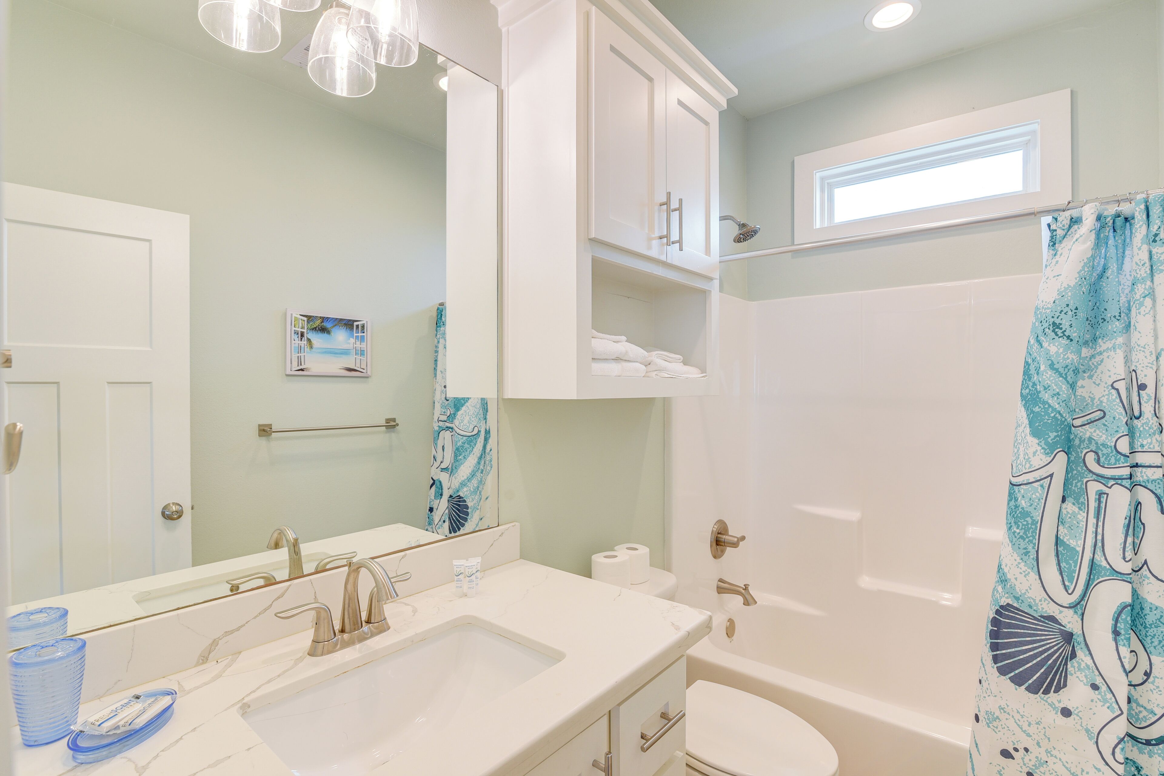 A bathroom with a sink, mirror, and shower.