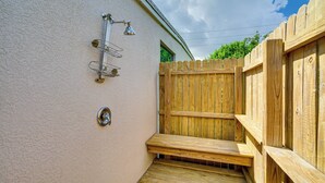 Eine Holzterrasse mit Metallgeländer, einem Holzzaun und einer wandmontierten Leuchte.