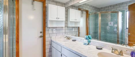 A bathroom with a large mirror, two sinks, and a shower area.