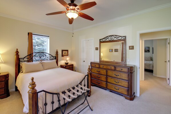 A bedroom with a bed, a dresser, a ceiling fan, a window, and a door leading to another room. - Clark Fork Riverfront Home w/ Dock! (Thompson Falls)