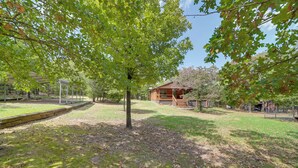 A cabin with a wooden deck, surrounded by trees and a grassy area. - Clayton Cabin w/ Wraparound Deck: Steps to Lake! (Clayton)