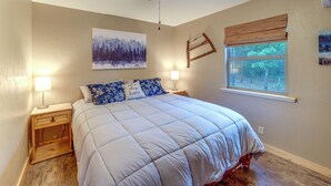 A bedroom with a bed, a ceiling fan, a window with a view, and a painting on the wall. - Clayton Cabin w/ Wraparound Deck: Steps to Lake! (Clayton)