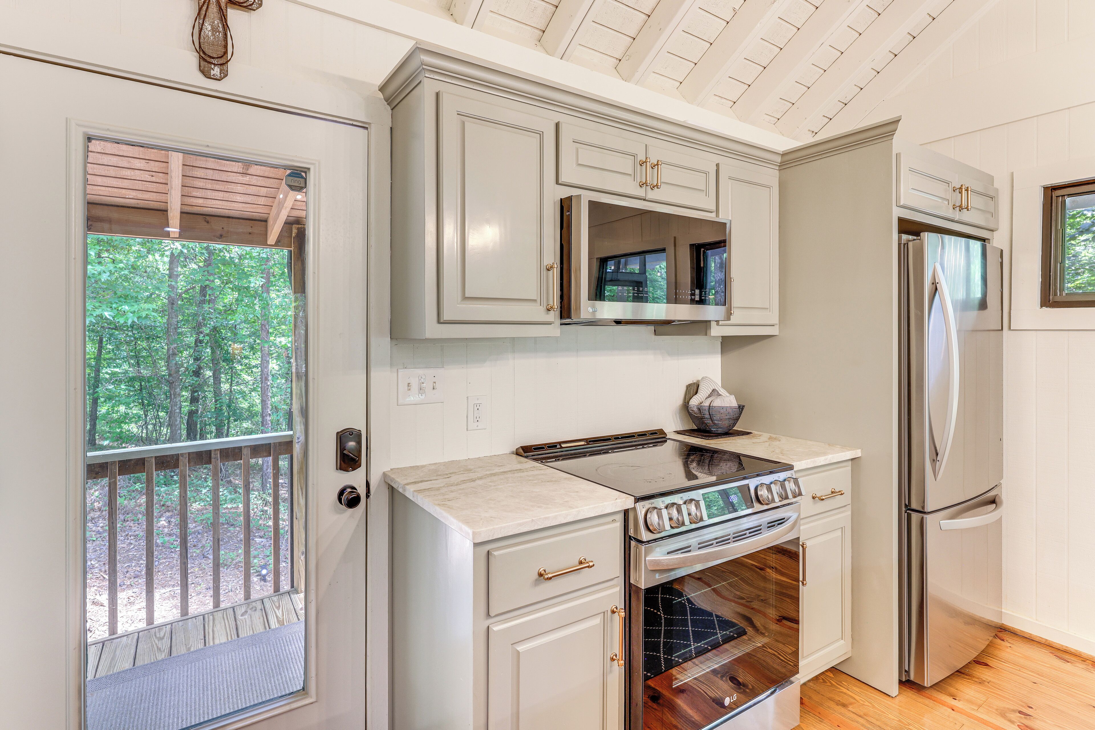 A compact kitchen with white cabinetry, a built-in oven, a microwave, and a refrigerator.