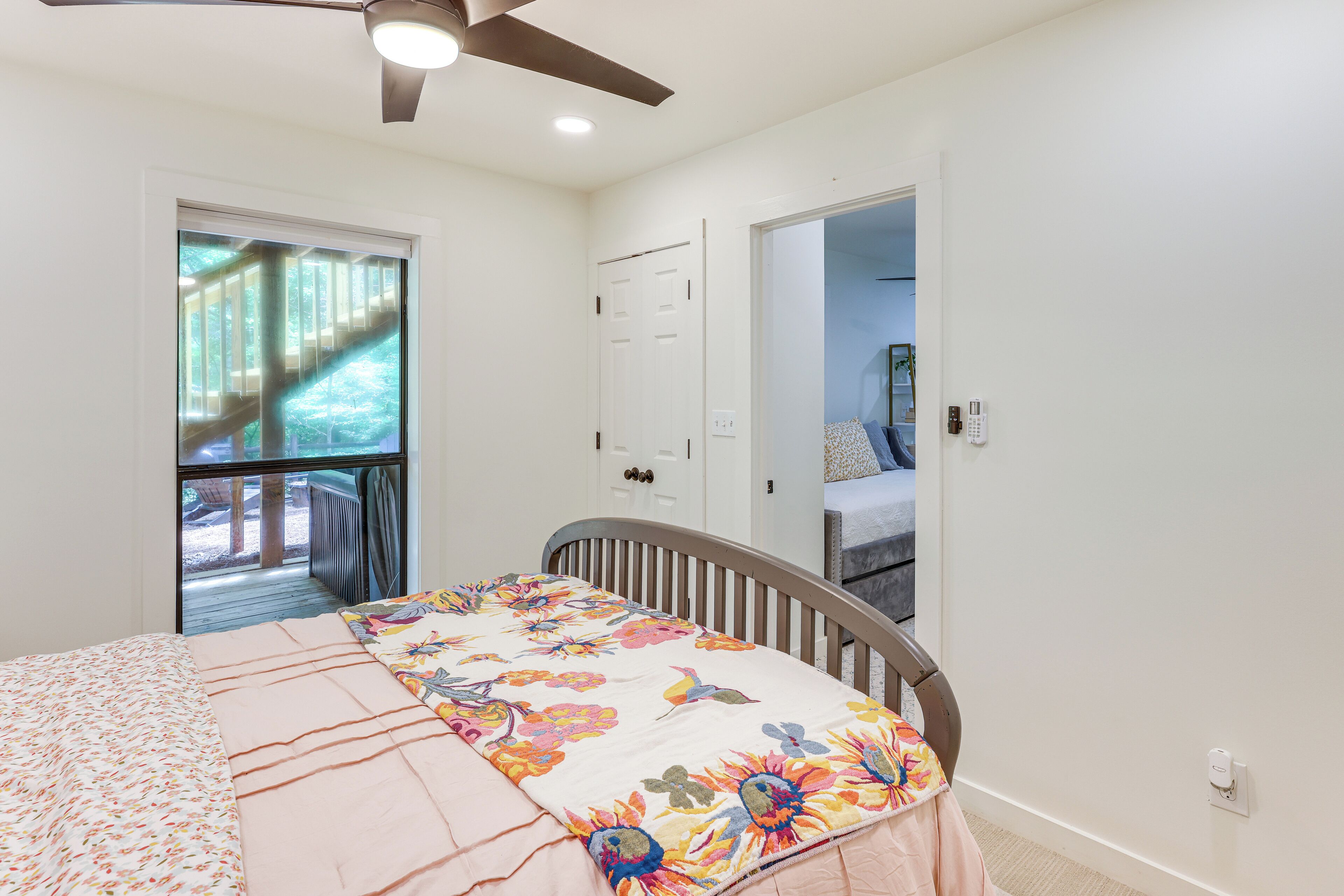 A bedroom with a bed, a ceiling fan, and a door leading to a balcony.