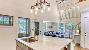 A spacious kitchen with a large island, a dining area with a wooden table, and a cozy seating area with a sofa. - Family-friendly Dadeville Cabin w/ Hot Tub & Porch (Dadeville)