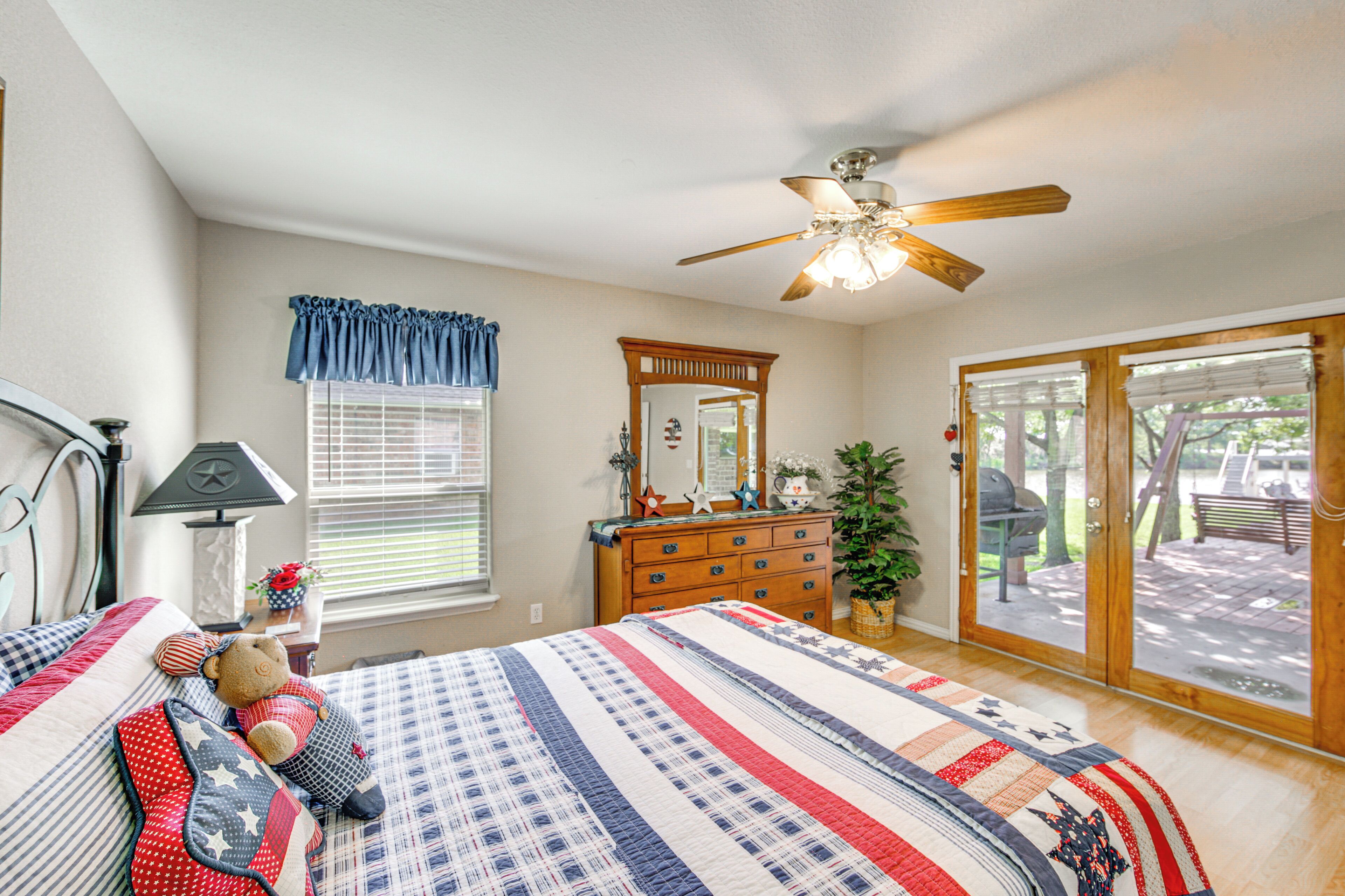 A bedroom with a bed, dresser, mirror, and a ceiling fan.