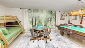 Una habitación con una mesa de billar, un sofá verde y una litera.