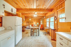 A wooden interior with a dining area, kitchen, and a clock on the wall.