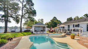 A backyard with a swimming pool, patio furniture, and a covered seating area. - Luxe Lakefront Portsmouth Home: Fish, Swim & Play! (Portsmouth)