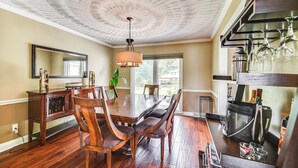A dining area with a wooden table and chairs, a chandelier, and a wine rack with glasses. - Luxe Lakefront Portsmouth Home: Fish, Swim & Play! (Portsmouth)