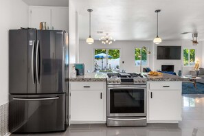 A modern kitchen with a stainless steel refrigerator, built-in oven, and granite countertop.