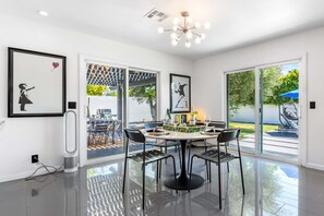 A modern dining area with a round table, black chairs, and a chandelier.