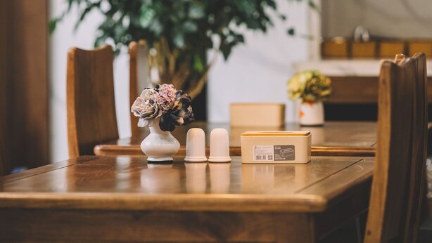 Una mesa de comedor con dos lámparas colgantes, un florero con flores, velas y una caja.