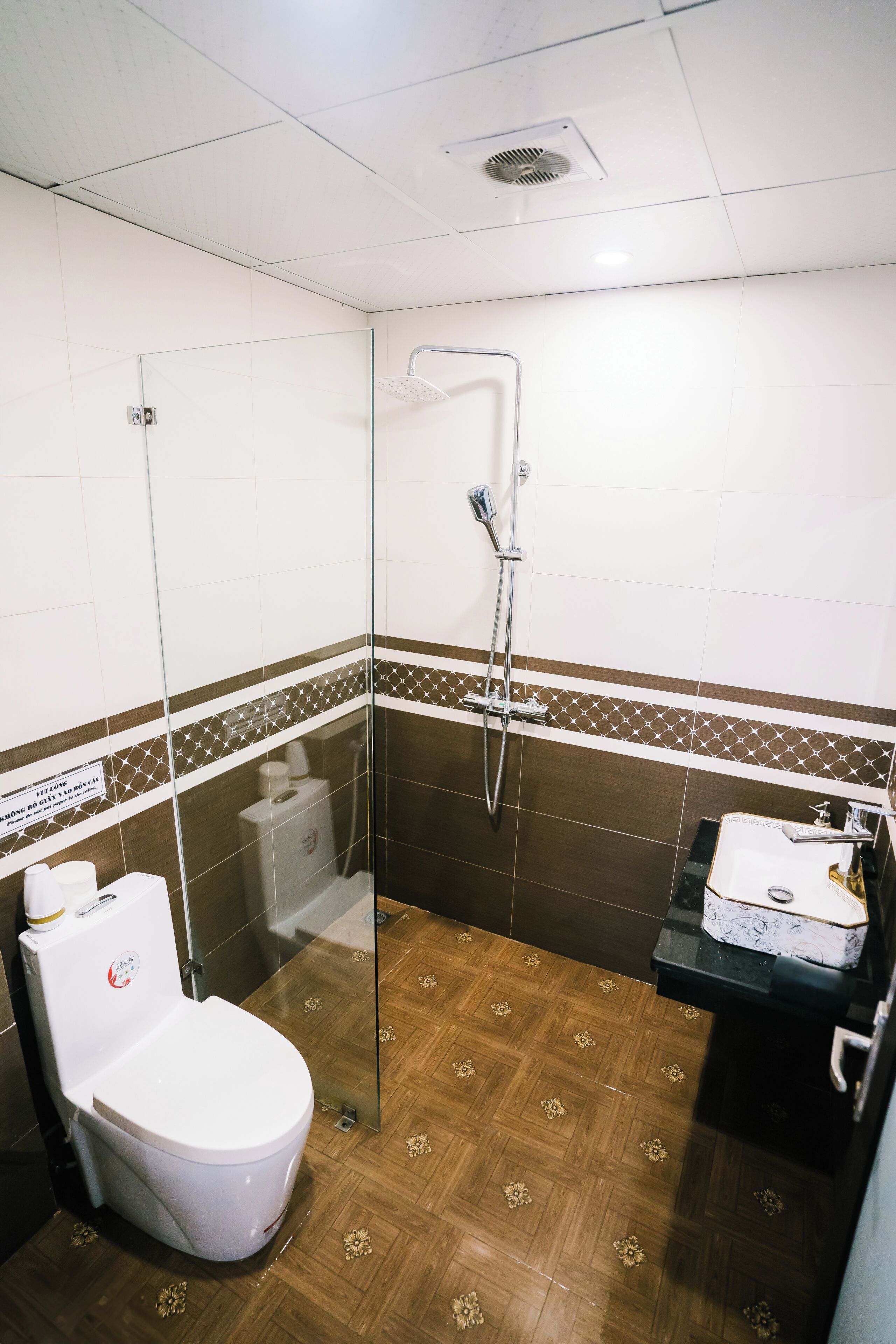 A bathroom with a glass shower enclosure, a toilet, and a sink area.