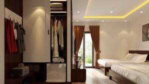 Una habitación de hotel con piso de madera, un armario con ropa colgada, una cama y una mesita con una tetera.