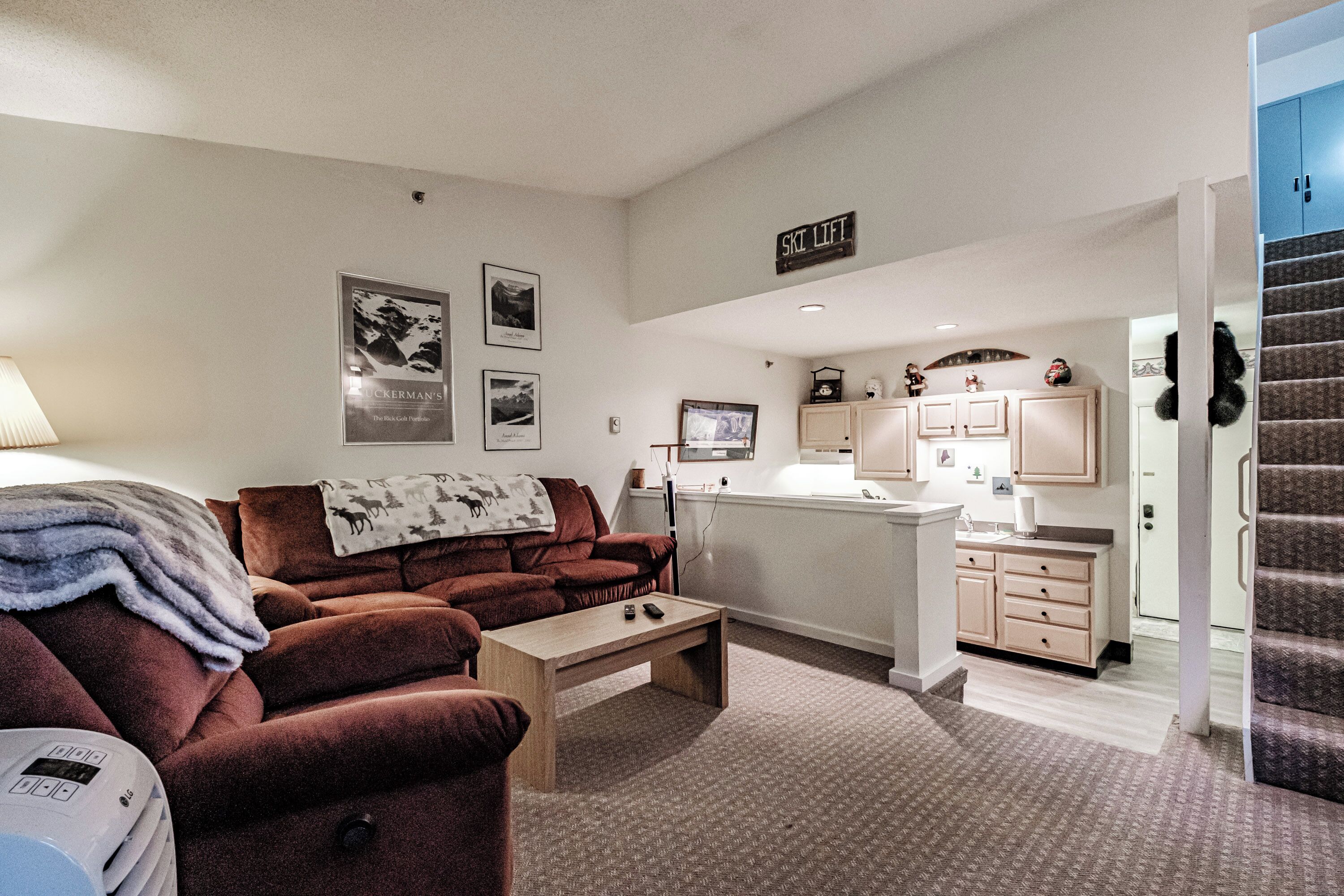 A compact living space with a sofa, a coffee table, a TV, and a kitchenette area.
