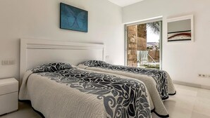 A bedroom with two beds, a large window, and a view of the outdoors.