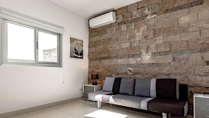 A modern living room with a stone wall, a sofa, a side table, and a window.