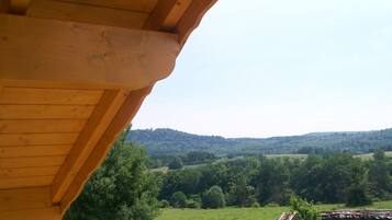 Una estructura de madera con vista a un paisaje verde y colinas al fondo.