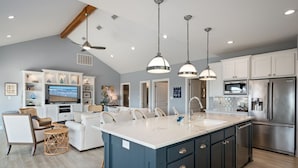A modern kitchen with a large island, built-in appliances, and pendant lighting.