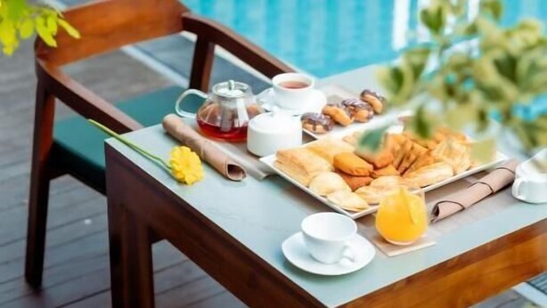 A dining table with breakfast items and a pool in the background. - KADUPUL By Serenity (Negombo)