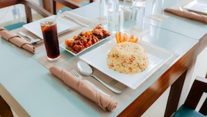A dining table with a plate of rice, a bowl of meat, and a glass of iced tea. - KADUPUL By Serenity (Negombo)