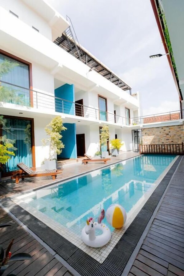 Una piscina al aire libre, sillones reclinables de piscina