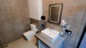 A modern bathroom with a white sink, a mirror, and a toilet.