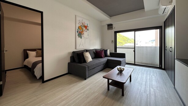 A modern living room with a grey sofa, a coffee table, and a painting on the wall. - Luxes Hijiyama 601 (Hiroshima)
