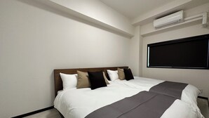 A hotel room with a large bed, a wooden headboard, and a wall-mounted air conditioner. - Luxes Hijiyama 601 (Hiroshima)