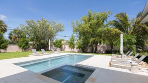 A rectangular swimming pool with a small hot tub, surrounded by a tiled deck and lounge chairs. - Larkshine House at Lunara Bay (Key West)