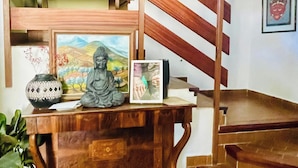 A wooden desk with a statue, framed artwork, and a vase. A staircase with wooden railings is in the background. - 3-bed Artist Chalet Near San Sebastian, Sleeps 6 (Arruazu)