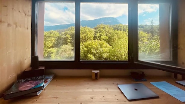 A room with a large window overlooking a forested area and mountains. There is a laptop and some books on the floor. - 3-bed Artist Chalet Near San Sebastian, Sleeps 6 (Arruazu)