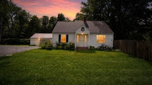 A small, single-story house with a front porch, a chimney, and a well-maintained lawn. - Stowe Retreat Mountain Views & Fenced Backyard by RedAwning (Stowe)