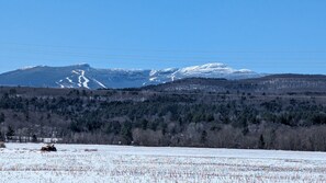 A snowy landscape with a mountain range in the background and a forested area in the foreground. - Stowe Retreat Mountain Views & Fenced Backyard by RedAwning (Stowe)