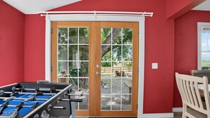 A room with a red wall, a wooden door, a foosball table, and a chair. - Stowe Retreat Mountain Views & Fenced Backyard by RedAwning (Stowe)