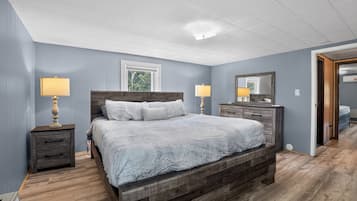 Um quarto com uma cama de madeira, duas mesas de cabeceira com abajures, um penteado e um espelho grande.