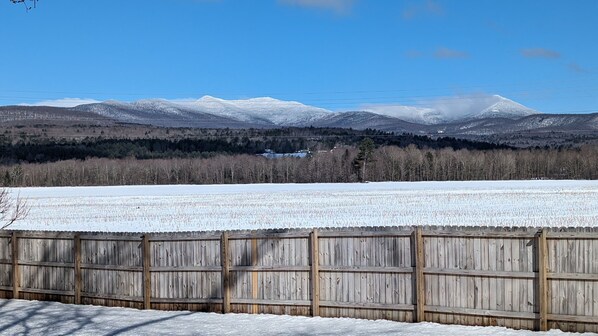 A snowy landscape with a wooden fence in the foreground and a mountain range in the background. - Stowe Retreat Mountain Views & Fenced Backyard by RedAwning (Stowe)