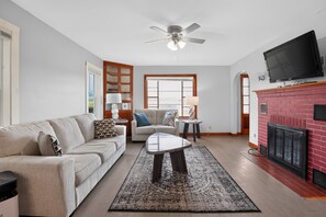 A living room with a sofa, coffee table, and fireplace. - Stowe Retreat Mountain Views & Fenced Backyard by RedAwning (Stowe)