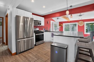 Una cocina moderna con electrodomésticos de acero inoxidable, una isla central y una pared de acento roja.